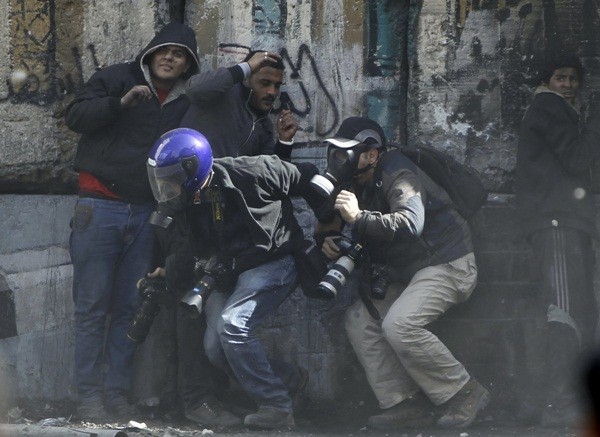  Các phóng viên ảnh đang co người lại khi những người biểu tình ném đá về phía cảnh sát chống bạo loạn trên tuyến đường Sheikh Rihan gần Quảng trường Tahrir, Cairo ngày 25/1/2013.