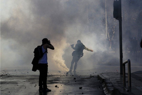  Một phóng viên ảnh đá hộp hơi cay ra xa trong một cuộc tuần hành ở thành phố Santiago, Chila, ngày 23/6/2011.&nbsp;