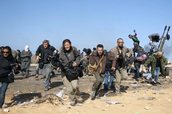  Các phóng viên, gồm phóng viên ảnh Tyler Hicks (bên phải đeo kính), Lynsey Addario (bên trái phía xa) của tờ New York Times, John Moore (thứ 2 bên trái) của tờ Getty Images, nhiếp ảnh gia tự do Holly Pickett (thứ 3 bên trái), &nbsp;Philip Poupin (thứ 4 bên trái) đang chạy trốn khỏi cuộc &nbsp;đánh bom của chính phủ Libya tại Ras Lanuf vào ngày 11/3/2011. &nbsp;