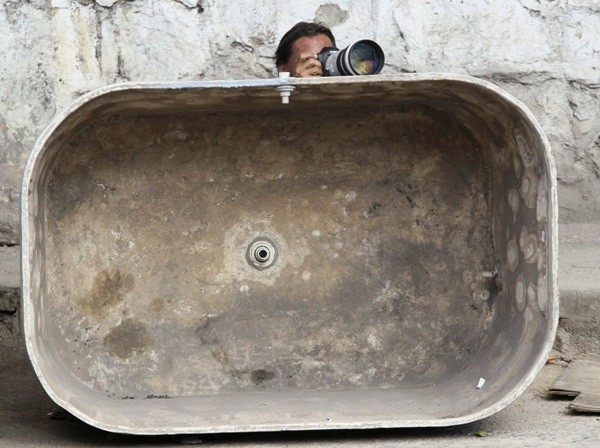  Một phóng viên ảnh tác nghiệp sau một bồn nước trong một chiến dịch nhằm vào khu ổ chuột Alemao ở Rio de Janeiro ngày 27/11/2010.&nbsp;