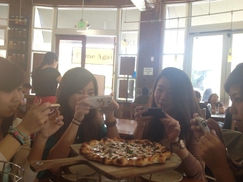 This picture of friends enjoying a delicious Brooklyn pizza: