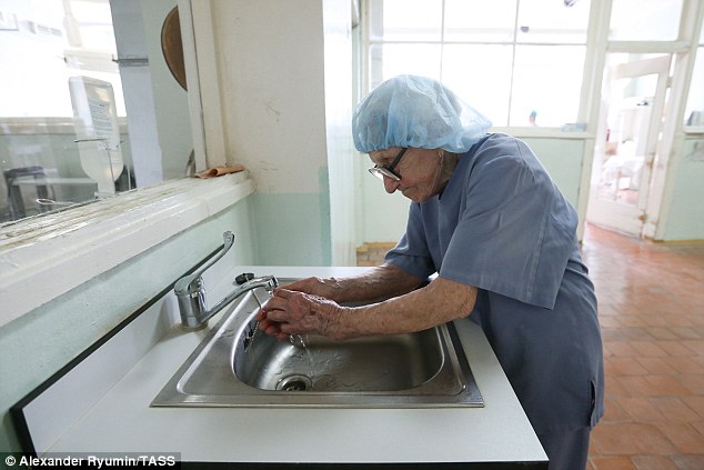  Bác sĩ Levushkina đội một chiếc mũ trùm và rửa tay trước khi vào một ca phẫu thuật 