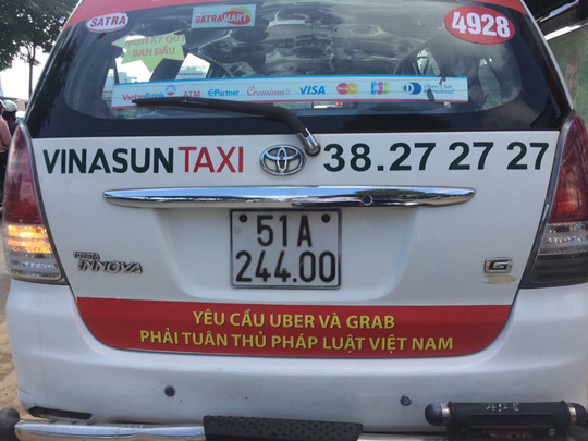 Khẩu hiệu phản đối Uber, Grab dán sau một taxi Vinasun lưu thông trên đường phố TP HCM sáng 8-10 - Ảnh: Lê Phong