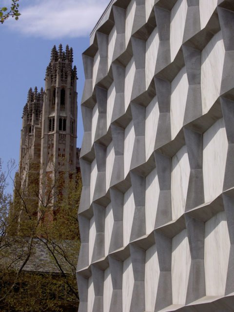  Vẻ ngoài với hình khối rắn chắc của Beinecke, điểm thêm các vòng xoắn kiểu Gothic của Trường Luật Yale ở nền 