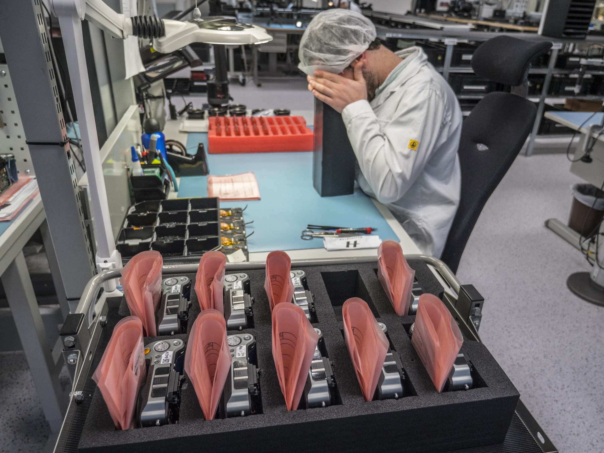 Chuyên viên khác đang nhìn vào hộp đen bao lấy thân máy để đảm bảo không có hiện tượng hở/lọt sáng nào trên màn hình LCD của máy