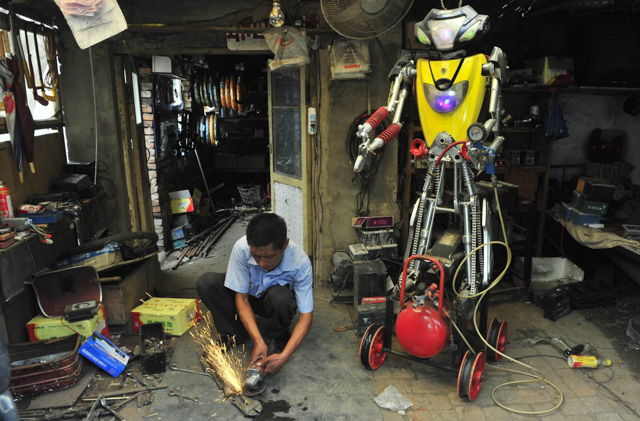Một thợ xe điện 49 tuổi đang thiết kế phụ tùng để lắp vào con robot của ông, Ảnh chụp vào ngày 25 tháng 6 năm 2012 tại tỉnh Liêu Ninh