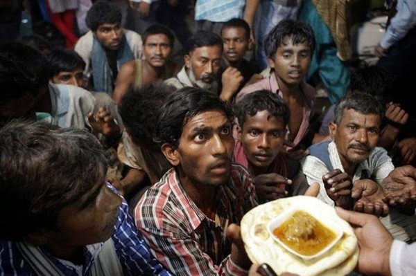  Đôi mắt cầu xin- Một nhóm những người vô gia cư đang giơ tay đón nhận phần thức ăn miễn phí của một tổ chức nhân đạo tại New Delhi, Ấn Độ. 