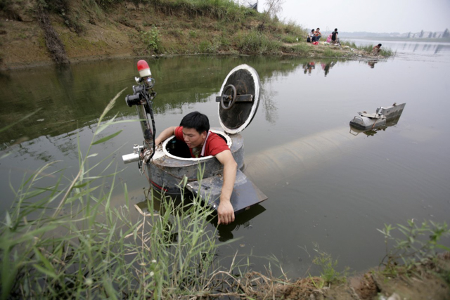 Tao Xiangli đang leo ra khỏi tàu ngầm tự chế của anh sau khi lặn tại hồ ở ngoại ô Bắc Kinh