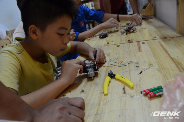  Một em nhỏ đang kiểm tra lại các mối nối trên con robot do chính tay mình lắp ráp. 