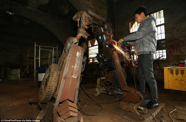 Lingin is seen in the makeshift factory father and son have made, making a metal model by welding together disused car parts 