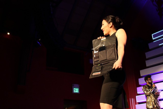 A model showing off a clutch that unfolds into a purse with pockets for devices.