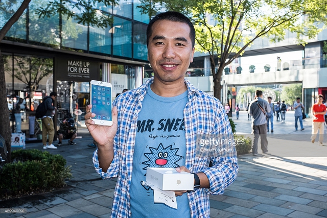  Một khách hàng khoe iPhone 6s mới trước cửa hàng Apple Store tại Bắc Kinh, Trung Quốc. 