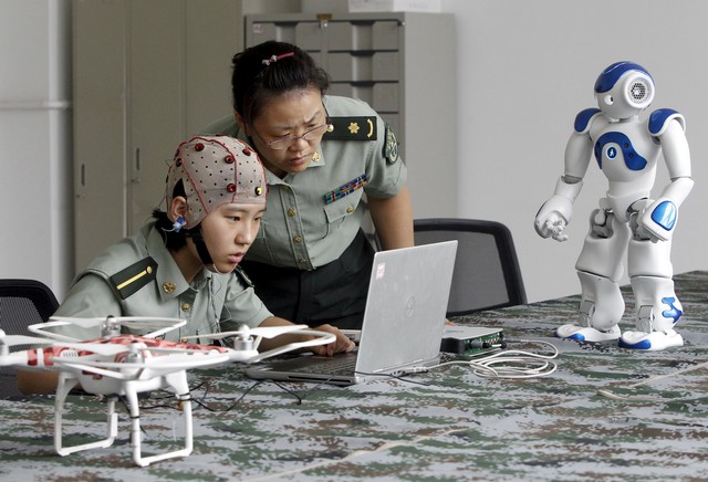  Một nữ sinh đang lắng nghe sự chỉ dẫn của giáo viên về cách sử dụng bộ thiết bị đeo để điều khiển robot tại trường ĐH. Kỹ thuật Thông tin PLA ở Trịnh Châu, tình Hà Nam, Trung Quốc. Ảnh Reuters. 