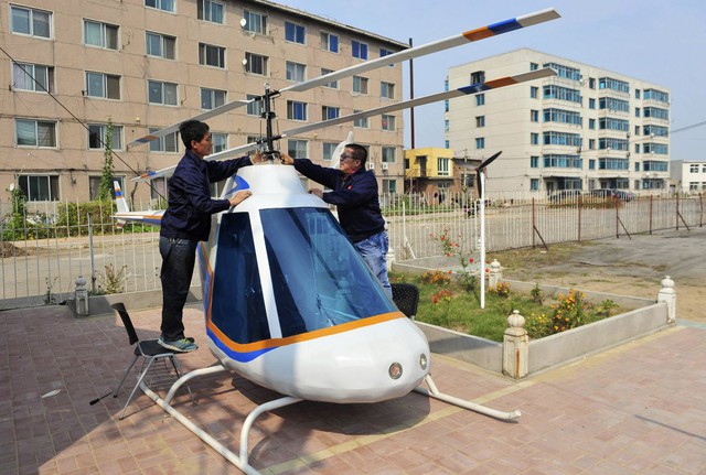  13. Tian Shengying (bên phải), một thợ rèn 55 tuổi, đang điều chỉnh các cánh quạt trên chiếc trực thăng “nhà làm” ở Thẩm Dương, tỉnh Liêu Ninh. 21/9/2012. 
