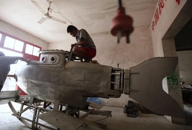  23. Một công nhân đang đánh bóng chiếc tàu ngầm mini còn đang thực hiện dang dở tại xưởng của Zhang Wuyi, một nông dân địa phương yêu thích các phát minh khoa học ở làng Qingling, ngoại ô Vũ Hán, Hồ Bắc vào 29/8/2011. 