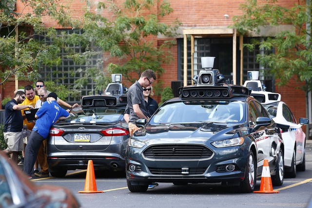  Nhân viên của Uber quanh những chiếc xe hybrid Ford Fusion trong buổi thử nghiệm xe. 