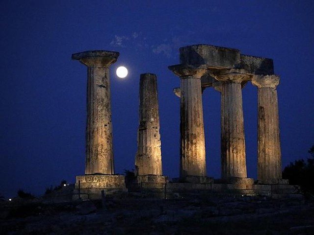 The super moon rises in the sky in front of the Apollo&apos;s temple at ancient Corinth about 