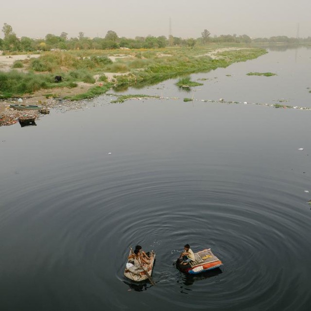  Trẻ em dùng xuồng lượn dọc sông Yamuna tìm kiếm những món rác thải có thể bán được 