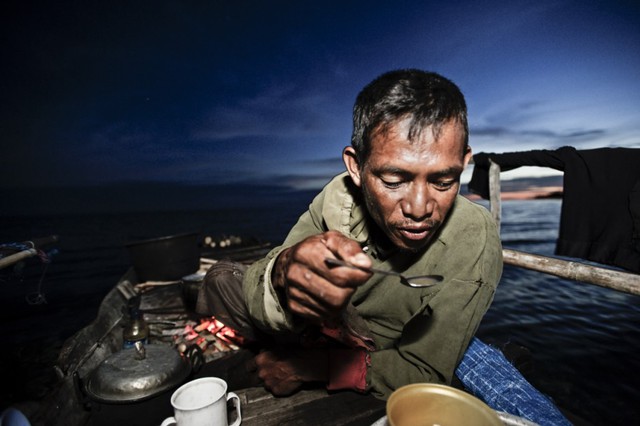  Người đàn ông ăn tối trên xuồng Lepa Lepa truyền thống, phần cuối xuồng để nấu ăn, phần giữa để ngủ và phần mũi để đánh cá 