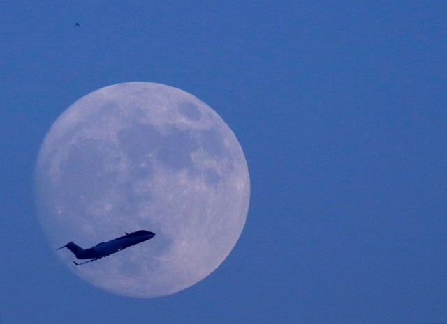 Máy bay bay ngang qua bầu trời Kathmandu ở Nepal, với hậu cảnh mặt trăng. Ảnh: Reuters.