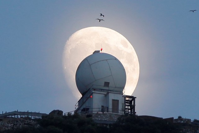 Trăng rằm dần xuất hiện trên nóc một tháp quan sát tại vùng lãnh thổ Gibraltar của Anh. Ảnh: Reuters.