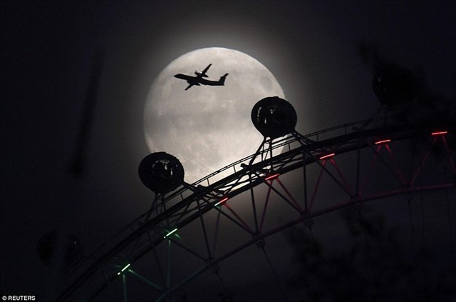 Một phi cơ bay trên nền trời trăng rằm ở thủ đô London của Anh. Ảnh: Reuters.