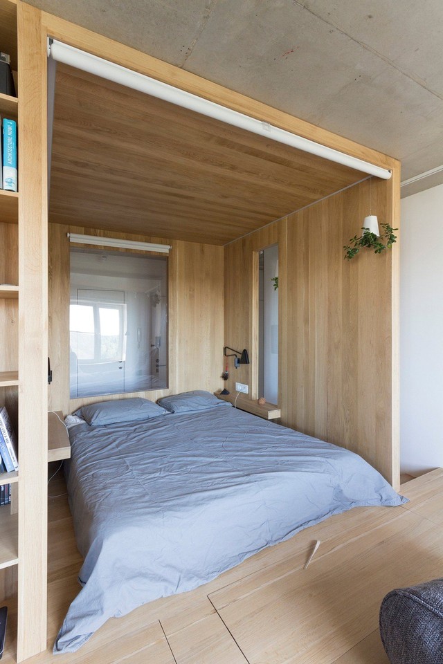  Phòng ngủ chỉ rộng 4m² nhưng êm ái, tiện nghi. Không có kệ đầu giường nhưng nhờ kệ gỗ được tính toán kĩ từ khi thiết kế mà căn phòng này vẫn có giá đồ nhỏ nhưng rất tiện. Nếu muốn riêng tư, bạn chỉ cần kéo rèm là được. 
