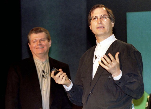  Vào cuối năm 1996, Apple thông báo dự định mang nhà sáng lập Steve Jobs trở lại công ty 11 năm sau khi ông rời đi bằng cách thâu tóm startup NeXT của ông với giá 429 triệu USD - vừa kịp thời gian để Jobs đứng cùng sân khấu với CEO Apple vào thời điểm đó là Gil Amelio trong sự kiện Macworld Expo vào tháng 1 năm 1997, một hội nghị dành cho những người yêu thích Mac. 