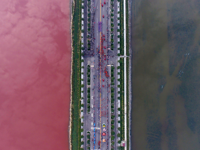  Một hồ muối có màu sắc rực rõ nhờ tảo, được phân cách bởi một con đường ở Vận Nam, Trung Quốc. 