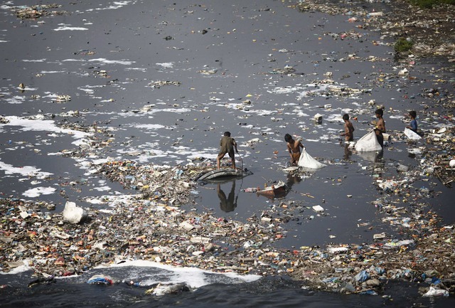 
Những đứa trẻ Nepal lượm vỏ chai nhựa trong một bãi rác với nước thải
