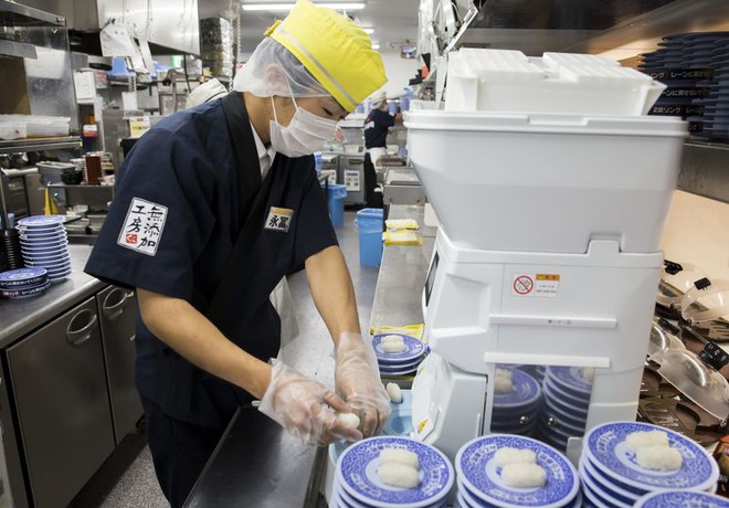 Một đầu bếp tạo nhà hàng Kura Corp đang sử dụng robot tại sushi. 