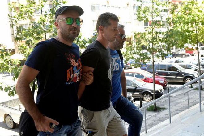  Alexander Vinnik (giữa) bị áp giải bởi 2 cảnh sát mặc thường phục. 
