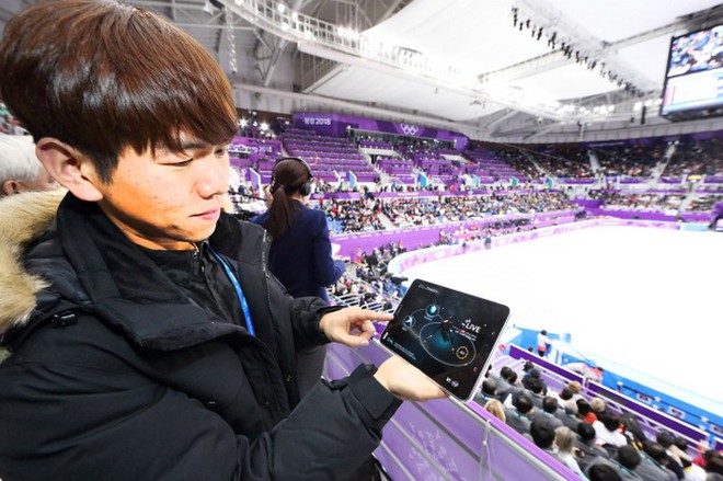  Một khán giả đang theo dõi một màn thi đấu tốc độ thông qua một thiết bị ứng dụng công nghệ Time Slice, cho phép quan sát mọi hình ảnh ở góc quay 180 độ nhờ sự hỗ trợ của 100 máy quay lắp đặt xung quanh sân Gangneung Ice Arena 
