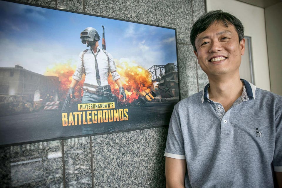 Một người đàn ông đứng cạnh màn hình hiển thị PUBG: Battlegrounds