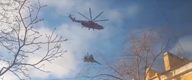 Máy bay chiến đấu Nga treo lơ lửng dưới bụng trực thăng bay qua bầu trời thành phố khiến dân mạng thích thú - Ảnh 1.