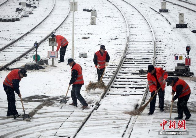  Công nhân đường sắt ở Giang Tây quét dọn tuyết chờ đoàn tàu vào ga. 