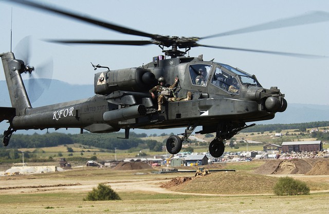  Một chiếc AH-64 trong buổi diễn tập giải cứu tại Camp Bondsteel, Kosovo năm 2007 với một lính Mỹ ngồi vắt vẻo bên ngoài. 