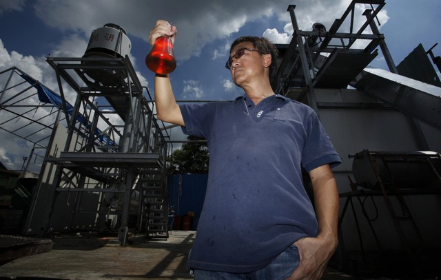 
Giám đốc Ming Cheung đang cầm trên tay bình dầu được chuyển đổi từ rác thải nhựa tại nhà máy của ông, ngoại ô Hồng Kông.
