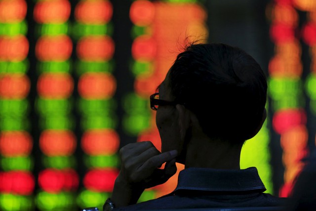  Một nhà đầu tư đang nhìn vào bảng điện tử của một sản giao dịch chứng khoán tại Thượng Hải, Trung Quốc. 