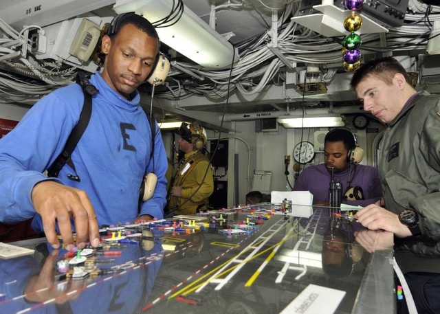  Một thủy thủ đang sắp xếp lại kế hoạch bay trong phòng trung tâm kiểm soát các chuyến bay trên boong tàu của tàu sân bay USS Abraham Lincoln. 