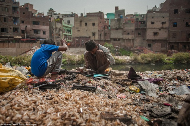Hai cậu bé tìm kiếm trong một bãi rác thải điện tử để chọn ra các bộ phận chứa kim loại có thể bán được.