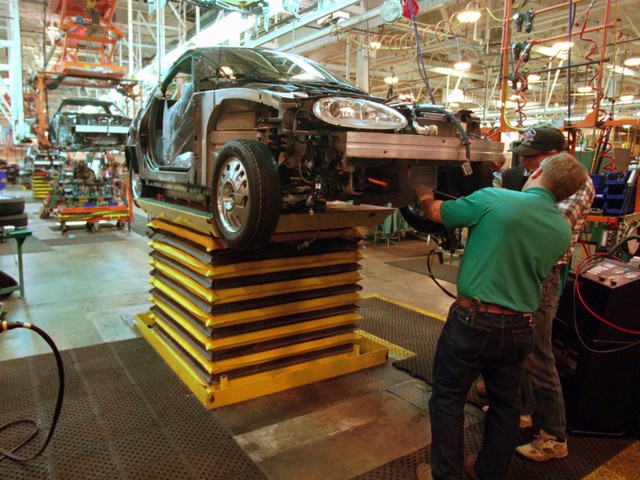  Công nhân tại một nhà máy General Motors lắp động cơ vào điện vào chiếc xe mới trong năm 1996. 