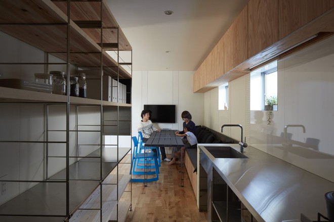  Căn bếp bao gồm một bàn dài, bàn nấu ăn làm từ thép không rỉ, ghế rocker xanh, dãy ghế mềm cùng với tủ đựng cùng màu với sàn nhà. 