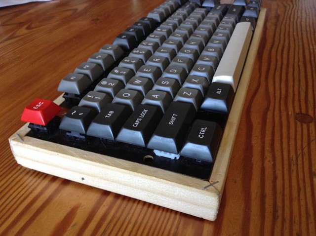 
Không phải cứ nhựa hay kim loại lạnh lẽo mới làm được lớp vỏ bàn phím cơ. Bản thân chiếc bàn phím của anh chàng EnigmaSA này được làm từ gỗ, đi kèm với layout 87 và bộ keycap DSA Dolch với gam màu trầm tối hợp gu với tổng thể chiếc bàn phím.
