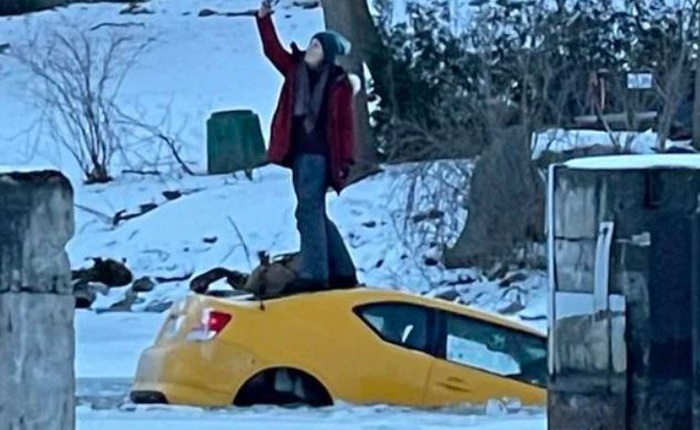 Xe sụt xuống hố băng, cô nàng thản nhiên leo lên nóc ngồi selfie với chiếc xe đang chìm nghỉm